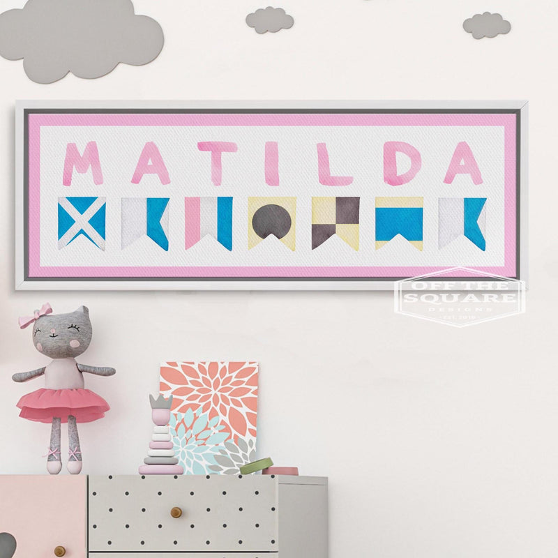 Personalized name canvas displayed above dresser, showing sample name "MATILDA" spelled in nautical signal flags with pink border and blue, cream, and gray flag details
