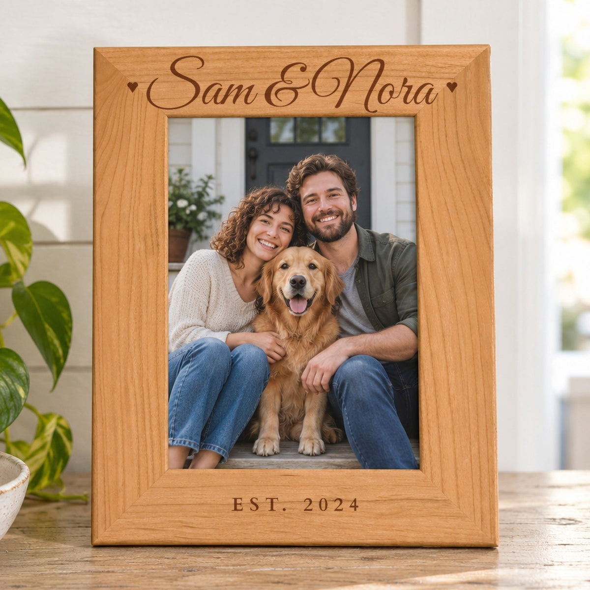 Side by Side engraved photo frame in red alder reading Sam &amp; Nora with hearts and EST. 2024, holding a couple and their dog on their front steps, on an entryway console