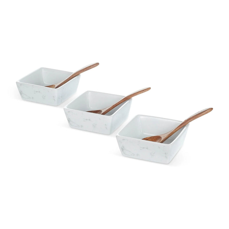 Three white marble bowls with wooden spoons displayed in a row