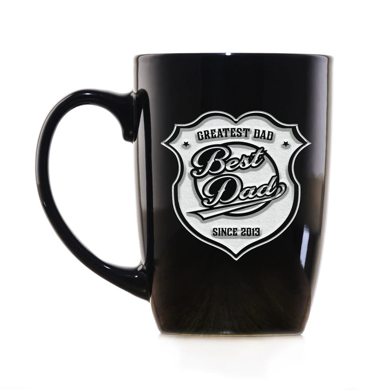Black 15 oz ceramic mug with engraved badge design reading "Greatest Dad Best Dad" and sample year "Since 2013" in silver relief lettering