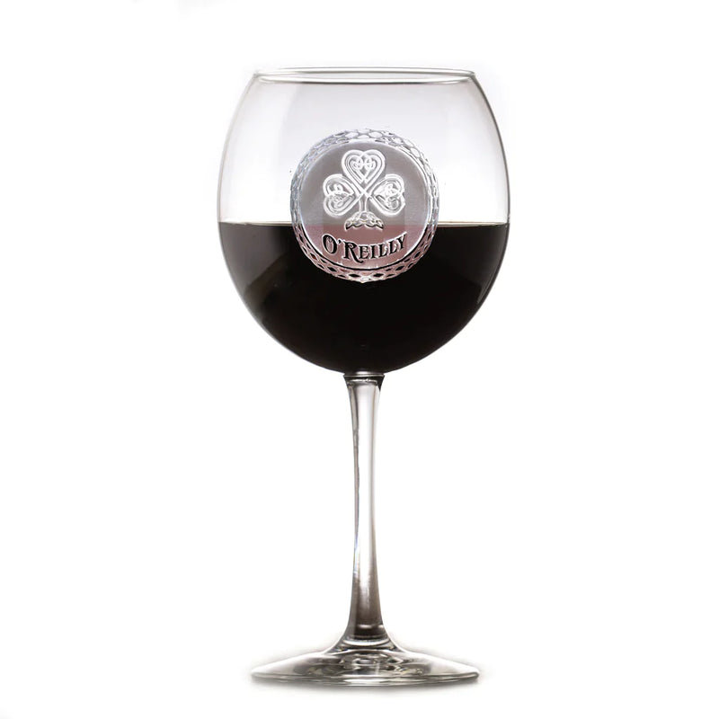 Wine glass filled with red wine, featuring an engraved circular medallion with a Celtic cloverleaf design and sample name "O'REILLY" on the bowl
