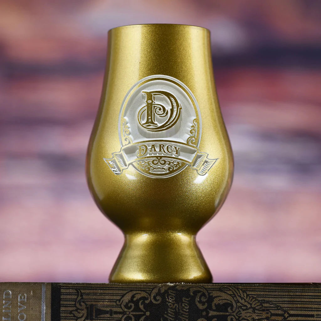Gold Glencairn whiskey glass with etched decorative crest featuring sample name "DARCY" in ornate banner design