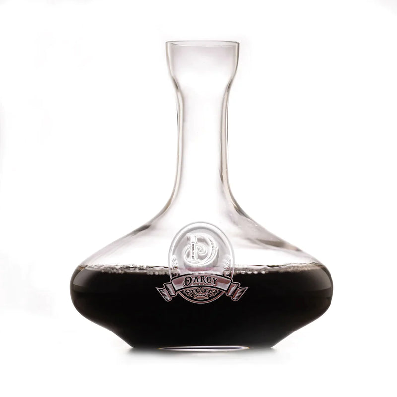 Clear glass wine decanter with wide bowl base and tapered neck, featuring an etched emblem with "DARCY" text and decorative banner design on the front