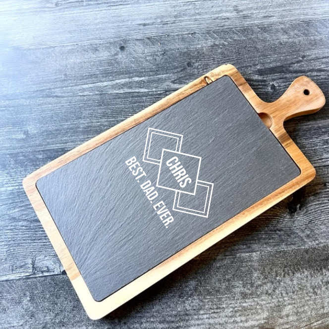 Slate and acacia wood serving board engraved with sample text "CHIPS & BEST DAD EVER" displayed on dark wood surface