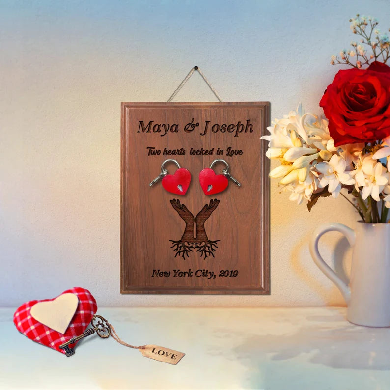 Walnut wood plaque engraved with sample names "Maya & Joseph," phrase "Two hearts locked in love," and location "New York City, 2010," decorated with red heart-shaped padlock