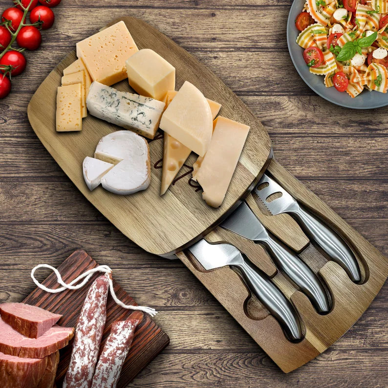 Light wood charcuterie board with trapdoor compartment, topped with assorted cheeses, cured meats, and cheese knives with stainless steel blades and handles