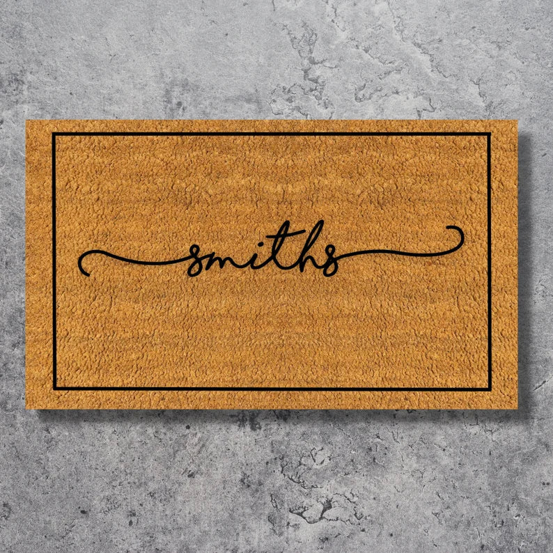 Natural coir doormat with black border and sample name "smiths" engraved in elegant script lettering across the center