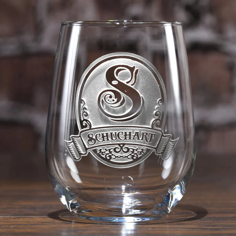 Stemless wine glass with ornate etched design featuring sample name "SCHUHART" and decorative initial "S" in oval cartouche with flourish details
