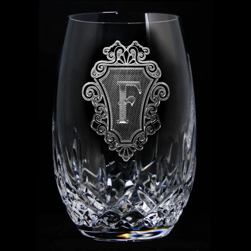 Crystal stemless glass with deeply engraved ornamental frame containing sample monogram letter F and textured diamond pattern at base
