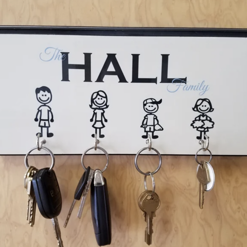 White key holder with "The Hall Family" text and four stick figures representing family members, each with a metal hook below for hanging keys